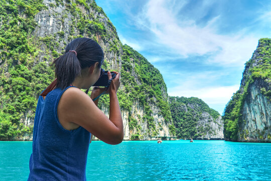 View from back tourist asian woman wear blue undershirt and take seascape photo Phi Phi island local area in Krabi Thailand.