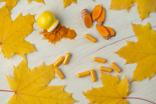Background with turmeric in different shapes Capsules and powder in a mini yellow pot and root cut into pieces