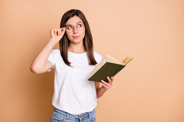 Photo portrait of clever female student in casual outfit keeping book looking blank space isolated...