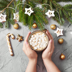 Christmas coffee cup with marshmallows. Female hands hold cup on background Christmas tree. Merry christmas and new year flat lay. Winter celebrations, vacations and weekends. Christmas food