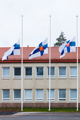 Three finnish flags lowered to half mast on the occasion of mourning at cloudy autumn day