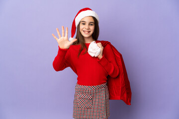 Little girl with hat and Christmas sack isolated on purple background counting five with fingers