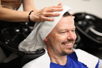 Master washes his head in barbershop. Beauty salon services concept