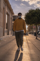African American black man with yellow sweatshirt walking down the street with the sun in the background