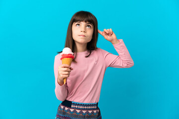 Little girl with a cornet ice cream isolated on blue background having doubts and thinking