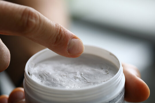 In hands of jar of white cream. Cosmetic products concept