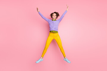 Fototapeta na wymiar Full length photo of careless childish girl jump raise hands isolated over pastel color background