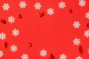 Winter design. White snowflakes, red berry in Christmas composition on red background for greeting card. Winter festive composition with copy space.