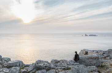 Fototapeta na wymiar Silhouette d'une personne admirant le paysage de la pointe de Pen Hir en Bretagne au coucher de soleil