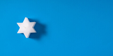 Christmas minimal composition. Candle star on blue background. Xmas, New Year, winter concept. Flat lay, top view, copy space