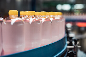 Fototapeta premium Bottling factory - Juice bottling line for processing and bottling lemon juice into bottles. Selective focus.