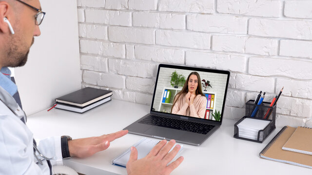 Nervous Panic Attack Woman In Computer Screen Talk With Medical Worker. Doctor Man In Hospital Office Soothes Patient Client With Breathing Technique Online Remote Distance Laptop Video Call Webcam