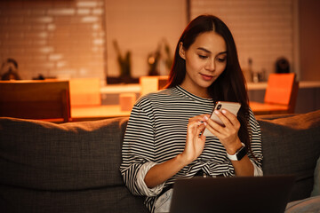 Focused charming woman using cellphone while working with laptop