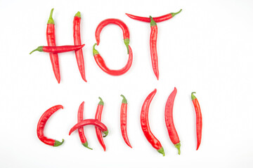 Red hot chili peppers are lined with letters on a white background. Vitamin vegetable food