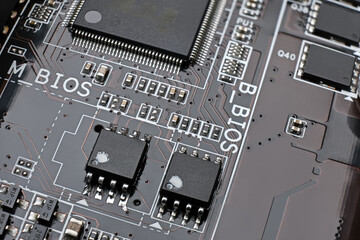 Brown motherboard pcb close up shot with dual bios chips, surface mount transistors, capasitors and...