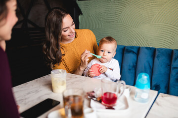Two friends enjoying in cafe bar with cute little baby boy.