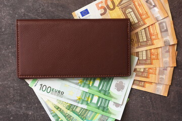 European currency money euro in a brown leather wallet on a dark background, COPY SPACE FOR TEXT