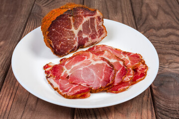 Partly sliced dried pork neck on dish, selective focus