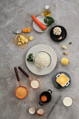 Ingredients for Making Cooking Arancini on a White Grey Marble Background. Cheese, Rice, Milk, Egg, Carrot, Parsley, Butter, Garlic, Bread Crumb, and Parmesan