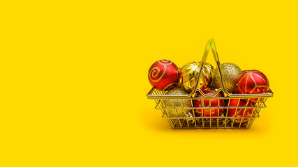 horizontal festive yellow background with copy space: toys on the Christmas tree in a metal shopping basket