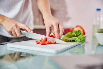Obraz na płótnie Canvas Knife cutting through a pepper on a board