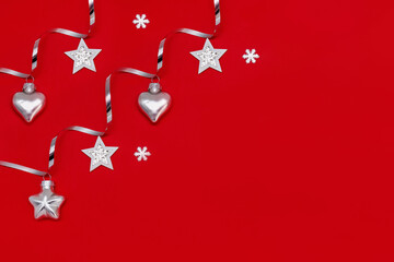 Flat composition of Christmas decorations in silver on a red background.