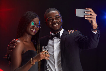 Waist up portrait of elegant African-American couple taking selfie photo while enjoying party © Seventyfour