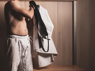 Unrecognizable male judoka putting on white judogi