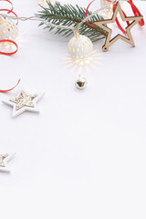 Christmas composition of wooden stars, a garland of white luminous balls, fir branches, bells and a red ribbon on a white background.