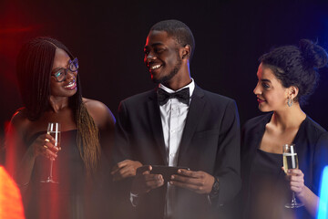 Waist up portrait of multi-ethnic group of friends smiling happily while enjoying elegant party