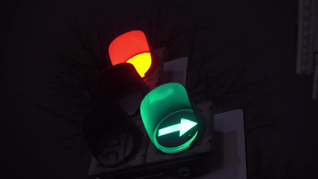 Red yellow green traffic light on a night city street close-up. The right turn section is lit.
