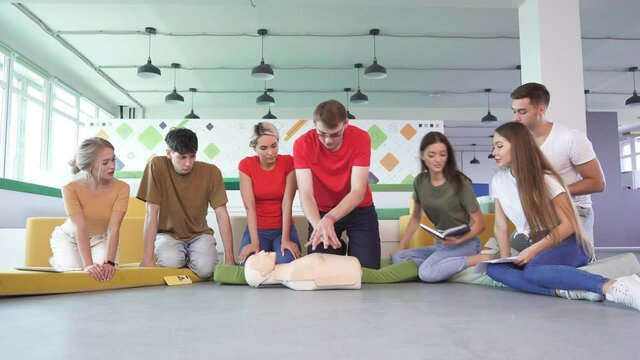 Video of first aid help on mannequin, two people help as team, practice cpr, heart compressions.