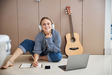 Cheerful female musician writing songs at home
