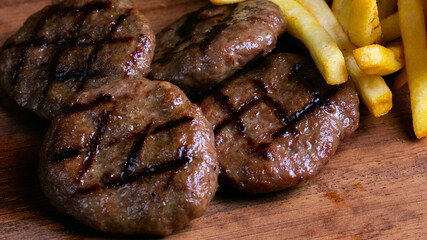 Delicious turkish grilled beef meatballs(mangal kofte) with crisp french friesh isolated on a wooden background close up.