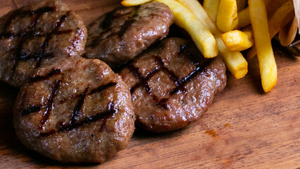 Delicious turkish grilled beef meatballs(mangal kofte) with crisp french friesh isolated on a wooden background close up.