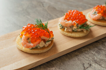 Toast skagen - classic Swedish appetizer. Sandwiches with shrimps and caviar on dark table....