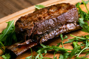 Delicious grilled short beef ribs with green isolated on a wooden(bamboo) tray close up.