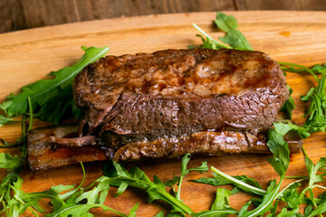 Delicious grilled short beef ribs with green isolated on a wooden(bamboo) tray close up.