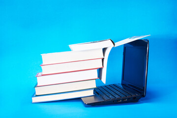 laptop and stack of books on yellow background