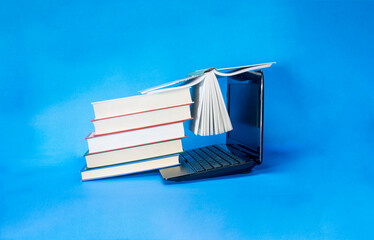 laptop and stack of books on yellow background