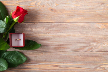 Valentines background with red rose and golden ring on the wooden table, flat lay, border with copy space