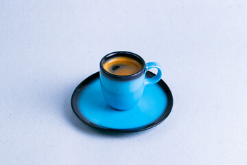 Espresso in a little blue ceramic cup isolated on a white background close up.