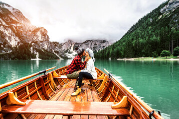 Romantic kiss of a couple of adults visiting an alpine lake at Braies Italy. Tourist in love spending loving moments together at autumn mountains. Couple, wanderlust and travel concept.	
