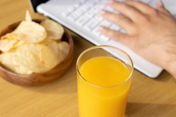 休憩時間におやつを食べ、ノートパソコンを使う男の手