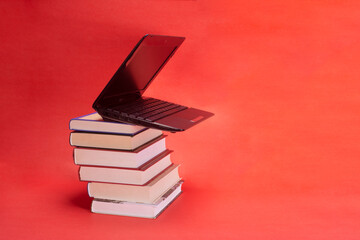 laptop and stack of books on yellow background