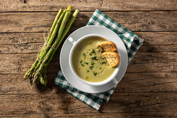 Fresh green asparagus soup in bowl on wooden table.Top view
