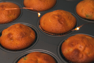 Tasty muffins with candied fruit slices close-up. Freshly baked cupcakes in molds and yellow...