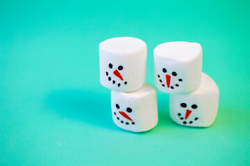 marshmallow snowmen ride on a sled on a turquoise background in  Christmas decorations