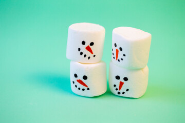 marshmallow snowmen ride on a sled on a turquoise background in  Christmas decorations
