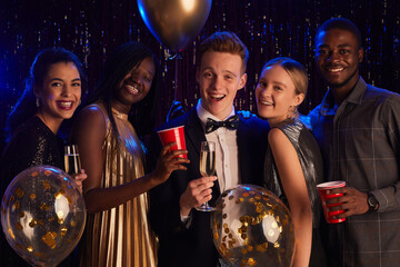 Waist up portrait of multi-ethnic group of friends smiling at camera happily while enjoying Birthday party or prom night